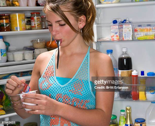 teen girl opens yogurt food - hungry teen stock pictures, royalty-free photos & images