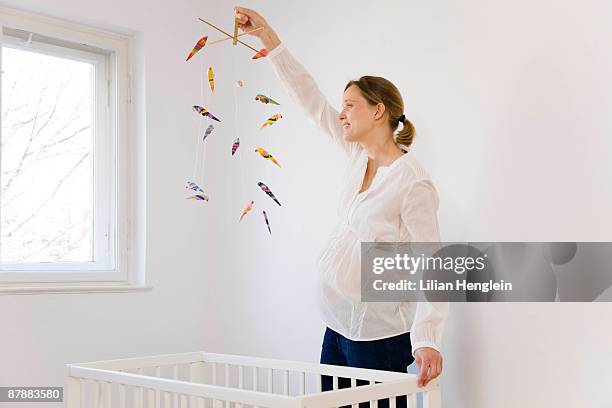 pregnant woman looking at mobile toy - baby mobile stock pictures, royalty-free photos & images