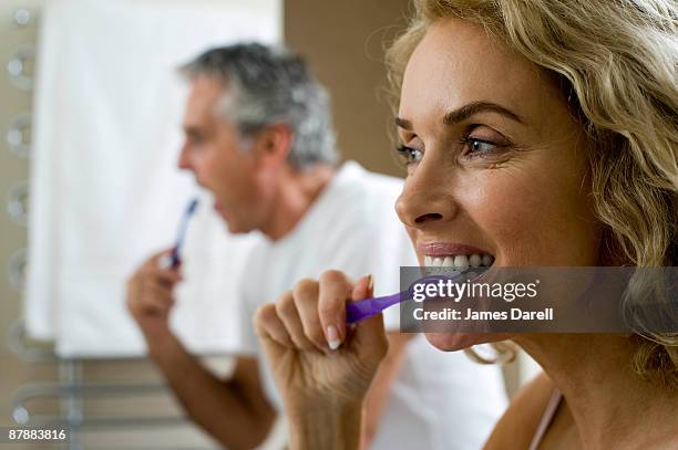 man and woman brushing teeth - brushing teeth stock pictures, royalty-free photos & images