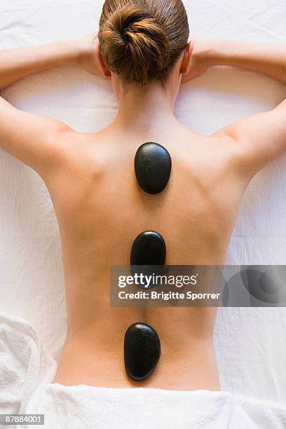 hot stones laying on woman's back - sauna und nassmassage stock-fotos und bilder