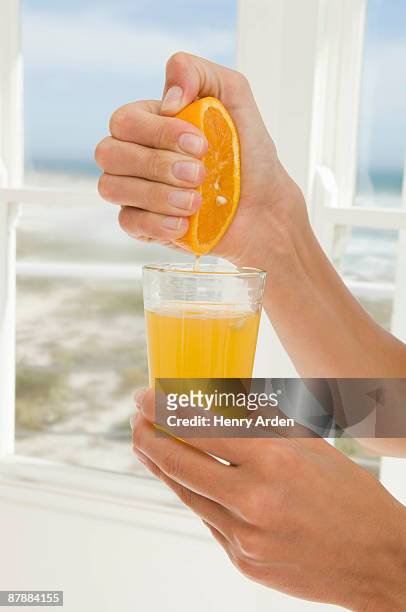 hand squeezing orange juice - woman squeezing orange stockfoto's en -beelden
