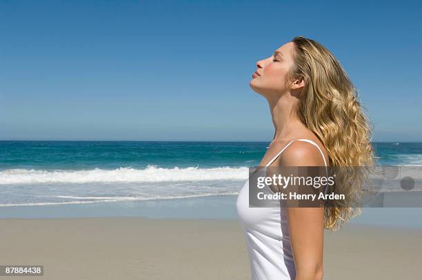 calm female on beach - blond hair young woman sunshine stock pictures, royalty-free photos & images