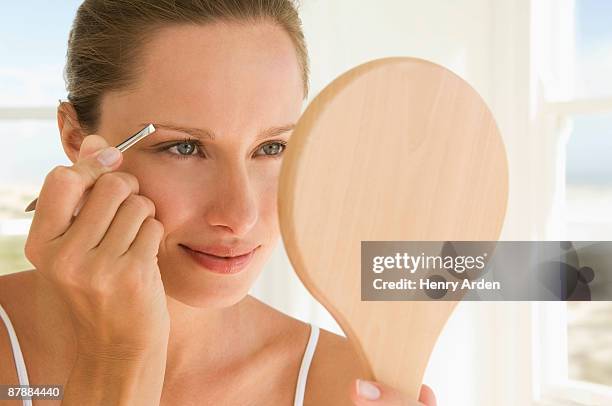 female beauty - tweezing eyebrows stock pictures, royalty-free photos & images