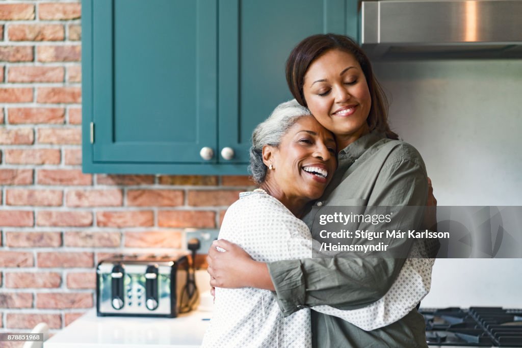 Smiling mid adult woman embracing senior mother