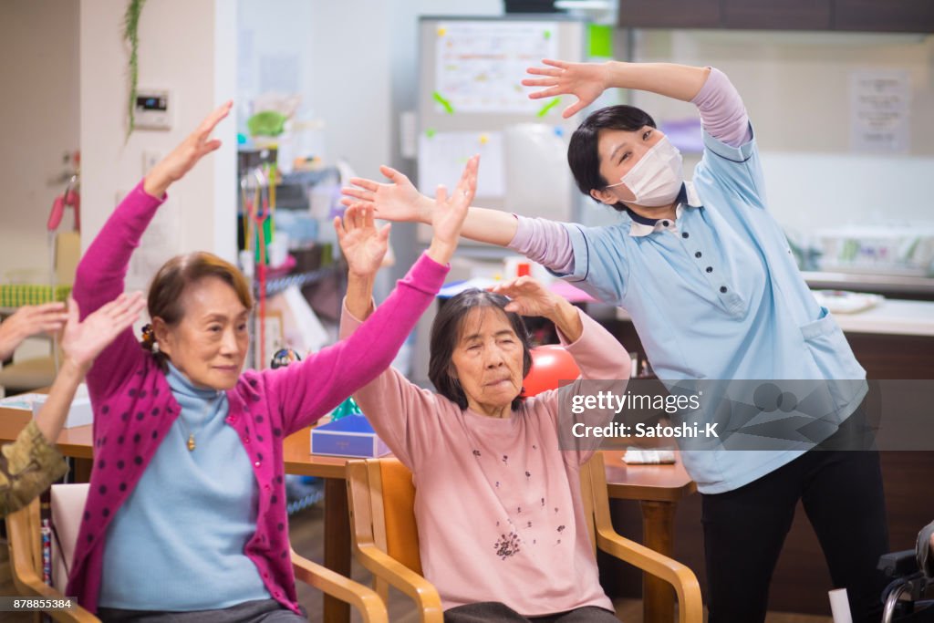 年配の女性と女性看護師のストレッチ