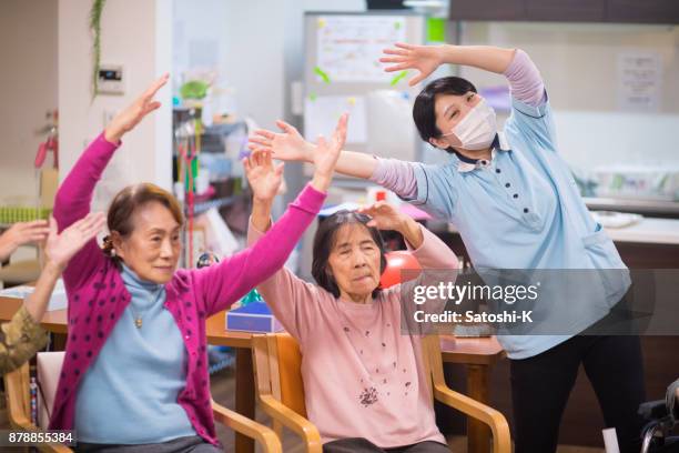 年配の女性と女性看護師のストレッチ - nursing home smiling ストックフォトと画像