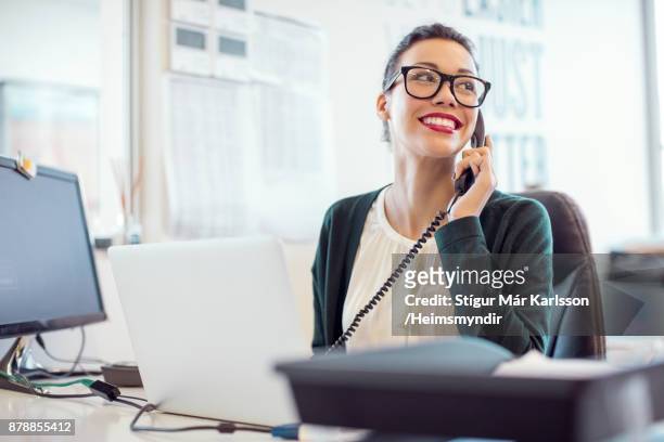 businesswoman talking on landline phone in office - telefone fixo imagens e fotografias de stock