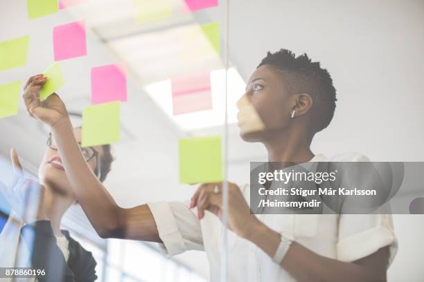 geschäftsfrauen diskutieren über haftnotizen - making stock-fotos und bilder