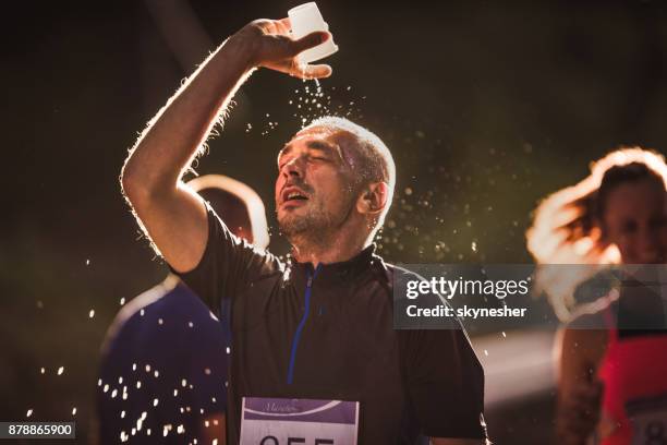 uitgeput stromende water van de loper op zijn hoofd tijdens marathon race in de natuur. - marathon stockfoto's en -beelden