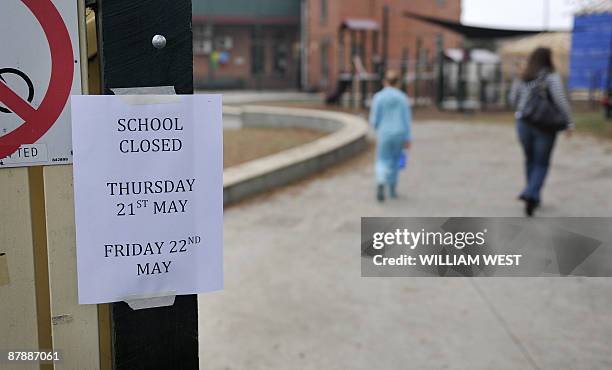 Woman and child walk past a sign on the gate of Clifton Hill primary school in Melbourne on May 21 which is closed until next week with its 51...