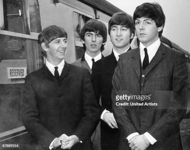 British rock group The Beatles stand next to a train on a station platform in Richard Lester's film 'A Hard Day's Night', 1964. Left to right, Ringo...