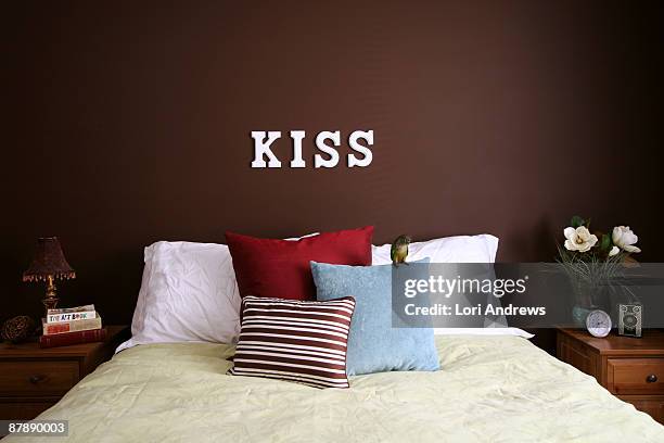 bed room - a woman modelling a trouser suit blends in with a matching background of floral print cushions stockfoto's en -beelden