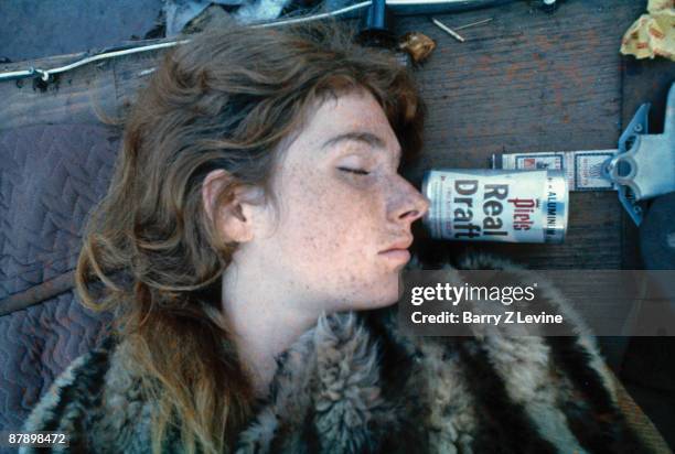 Close-up of an unidentified concert-goer asleep outdoors, next to a can of beer, at the Woodstock Music and Arts Fair in Bethel, New York, August 15...