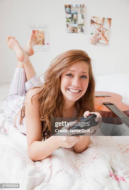 teenage girl playing a video game in bedroom - brown hair girl stock pictures, royalty-free photos & images