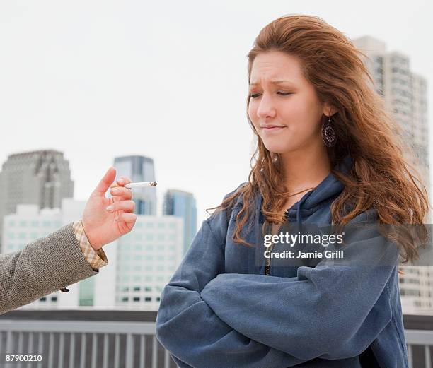 teenage girl next to friend offering cigarette - peer pressure stock pictures, royalty-free photos & images