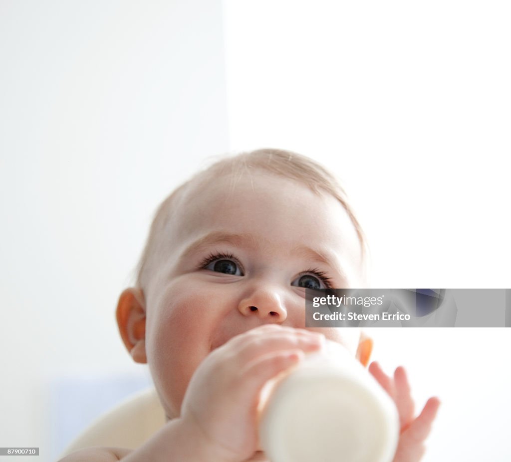 Baby girl (9-12 months) drinking from bottle.