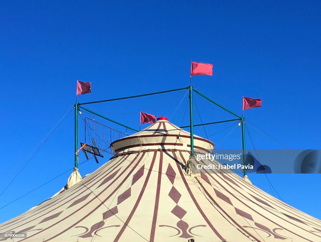 Circus tent with red flags against blue background