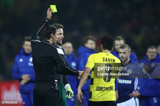 Referee Deniz Aytekin shows a yellow card to both Nuri Sahin of Dortmund and Ralf Faehrmann of Schalke after the Bundesliga match between Borussia...