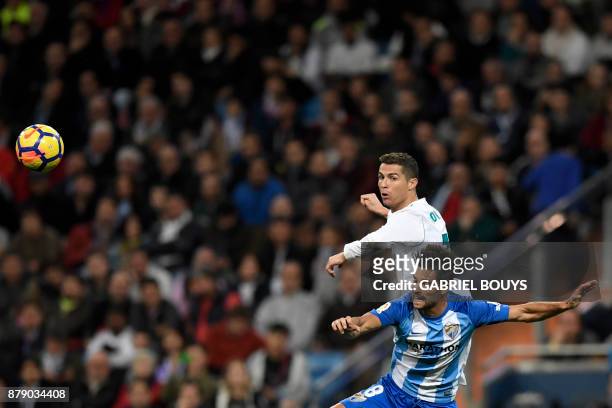 Real Madrid's Portuguese forward Cristiano Ronaldo and Malaga's Spanish midfielder Adrian Gonzalez Morales jump for the ball during the Spanish...