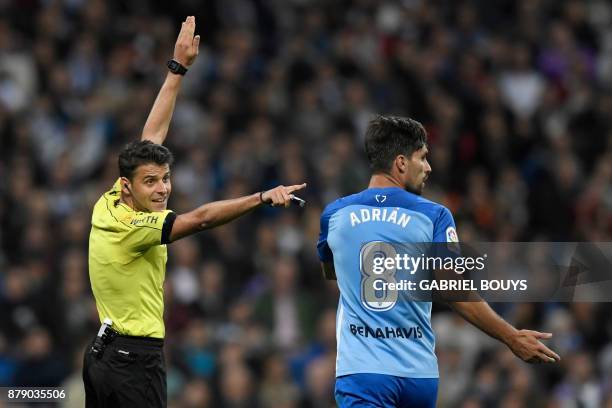 Spanish referee Jesus Gil Manzano gestures next to Malaga's Spanish midfielder Adrian Gonzalez Morales during the Spanish league football match Real...