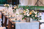 rest, food, party concept. wooden table numbered six prepared for holiday dinner and decorated with amazing grand bouquet of marvelous roses of white and orange color