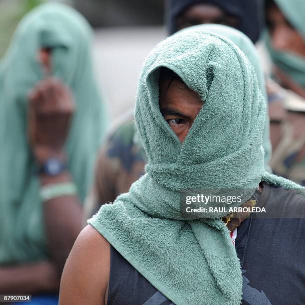 Members of "Los Rastrojos" bandit group cover their face with towels as they surrender at the Voltigeros Battalion on May 21, 2009 in Uraba,...