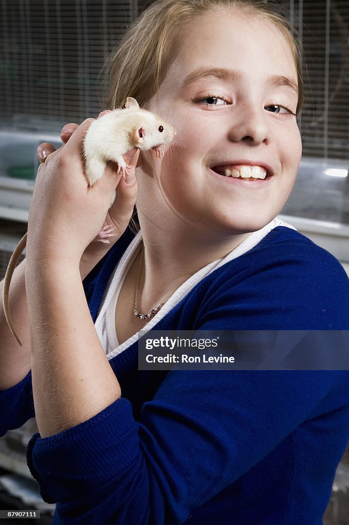 Young girl holding a rat in pet shop