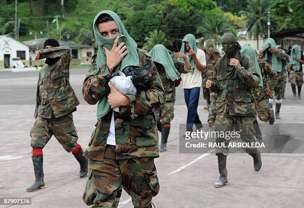 Members of "Los Rastrojos" bandit group cover their faces as they surrender at the Voltigeros Battalion on May 21, 2009 in Uraba, Antioquia...