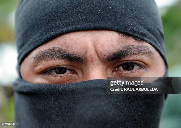 Member of "Los Rastrojos" bandit group covers his face with a balaclava as he surrenders at the Voltigeros Battalion on May 21, 2009 in Uraba,...