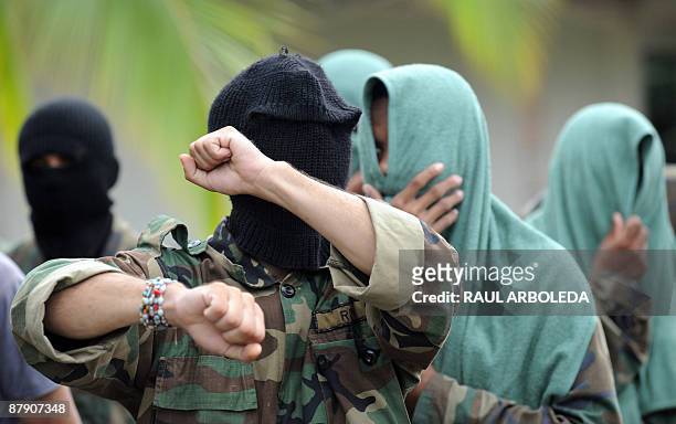 Members of "Los Rastrojos" bandit group cover their face with towels and balaclavas as they surrender at the Voltigeros Battalion on May 21, 2009 in...