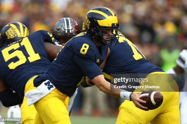 John O'Korn of the Michigan Wolverines goes to hand off the ball first half against the Ohio State Buckeyes on November 25, 2017 at Michigan Stadium...