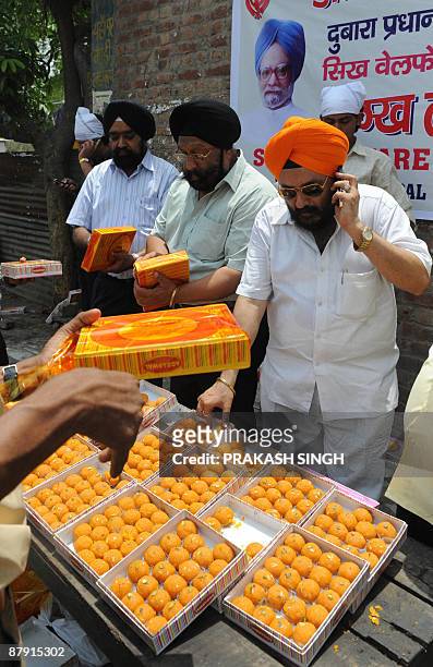 Members of Sikhs Welfare Society distribute sweets to celebrate the second term of Prime Ministership for Manmohan Singh at Gurudwara Racab Ganj in...
