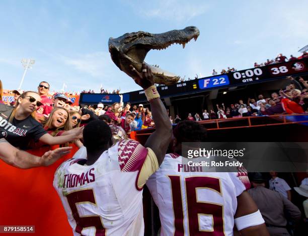Matthew Thomas and Jacob Pugh of the Florida State Seminoles carry a gator head out of Ben Hill Griffin Stadium after the game against the Florida...
