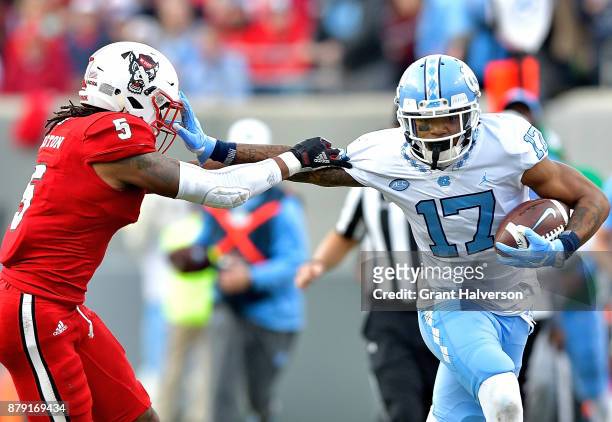 Anthony Ratliff-Williams of the North Carolina Tar Heels stiff-arms Johnathan Alston of the North Carolina State Wolfpack during their game at Carter...