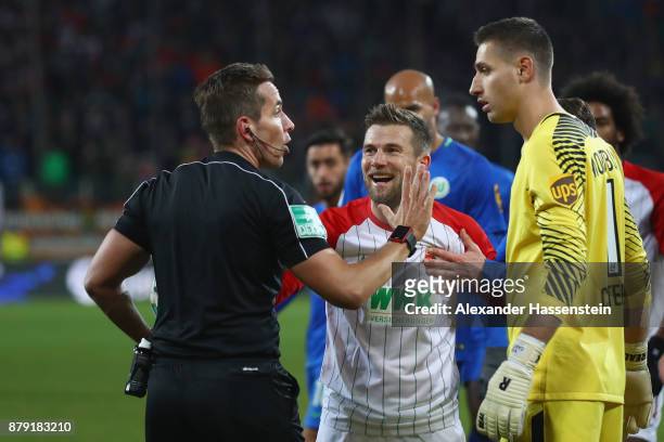 Referee Tobias Stieler reacts with Daniel Baier of Augsburg and Koen Casteels, keeper of Wolfsburg during the Bundesliga match between FC Augsburg...