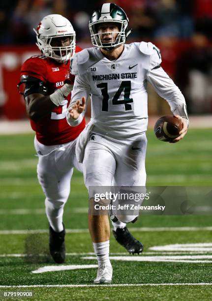 Brian Lewerke of the Michigan State Spartans runs from Kemoko Turay of the Rutgers Scarlet Knights during their game on November 25, 2017 in...