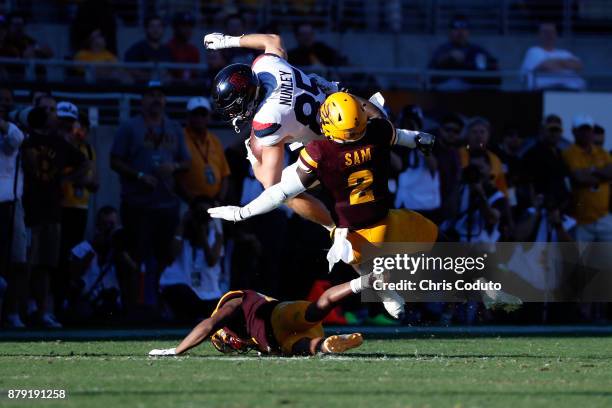 Tight end Jamie Nunley of the Arizona Wildcats is hit by linebacker Christian Sam and defensive back Chad Adams of the Arizona State Sun Devils and...