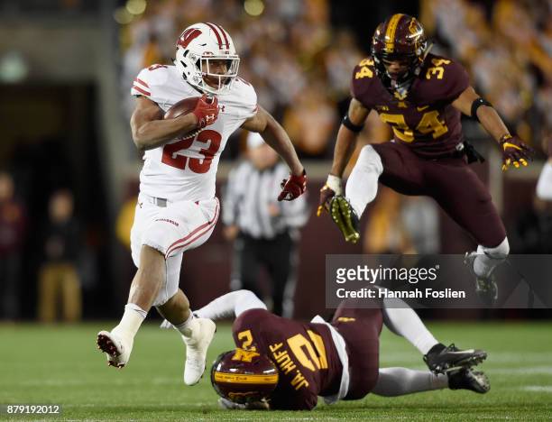 Jonathan Taylor of the Wisconsin Badgers carries the ball for a touchdown after avoiding a tackle by Jacob Huff and Antonio Shenault of the Minnesota...