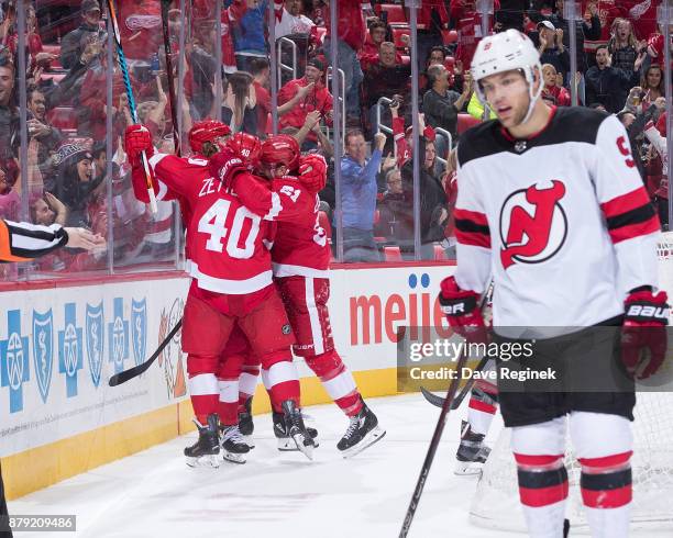 David Booth of the Detroit Red Wings celebrates his third period goal with teammates Henrik Zetterberg and Xavier Ouellet as Taylor Hall of the New...