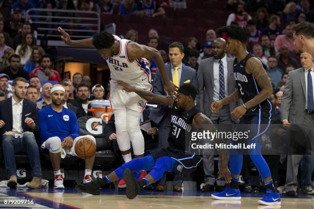 Joel Embiid of the Philadelphia 76ers and Terrence Ross of the Orlando Magic try to avoid touching the ball as it goes out of bounds in the fourth...