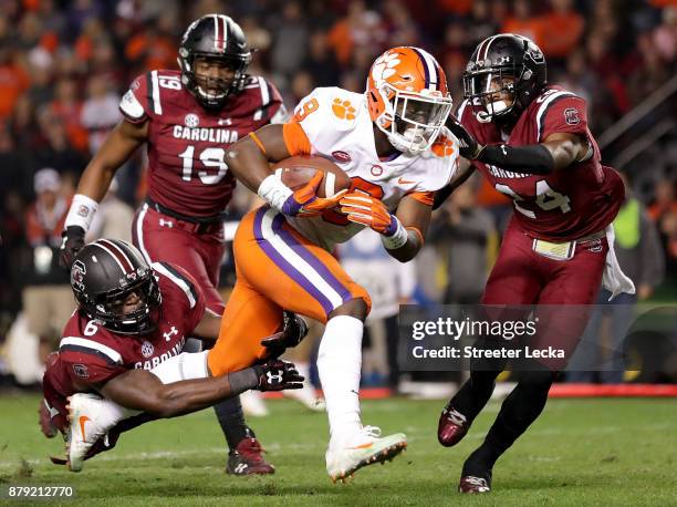 Travis Etienne of the Clemson Tigers runs for a touchdown as teammates T.J. Brunson and D.J. Smith of the South Carolina Gamecocks try to stop him...