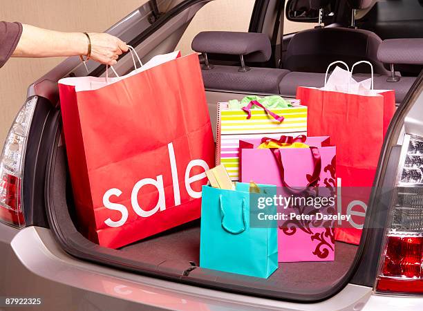 woman putting sale carrier bag in car boot. - car sale stockfoto's en -beelden