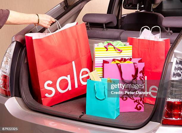 woman putting sale carrier bag in car boot. - boot sale stock pictures, royalty-free photos & images