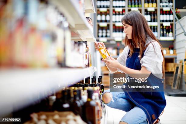 ストア内のドレッシングのボトルを調べる女性デリ所有者 - 息抜き ストックフォトと画像