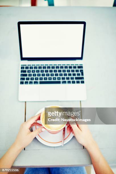 pov frau mit kaffeetasse mit laptop auf tisch - neustockimages stock-fotos und bilder