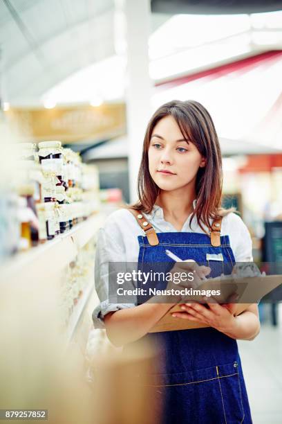 schöne deli inhaber hält zwischenablage und stift durch regale - neustockimages stock-fotos und bilder