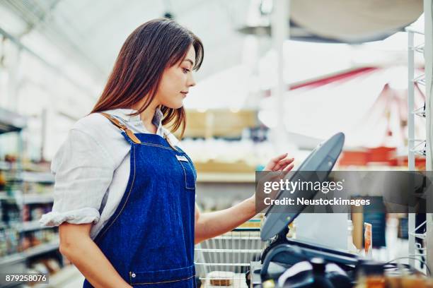 junge deli-besitzer mit kasse im shop - neustockimages stock-fotos und bilder