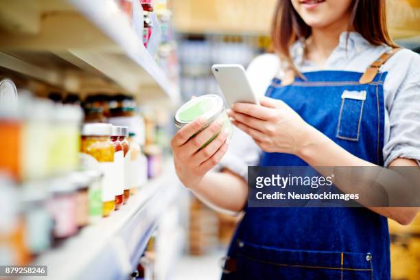deli eigenaar label op voedsel container met slimme telefoon scannen - conagra general mills brand products on the shelf ahead of earns stockfoto's en -beelden