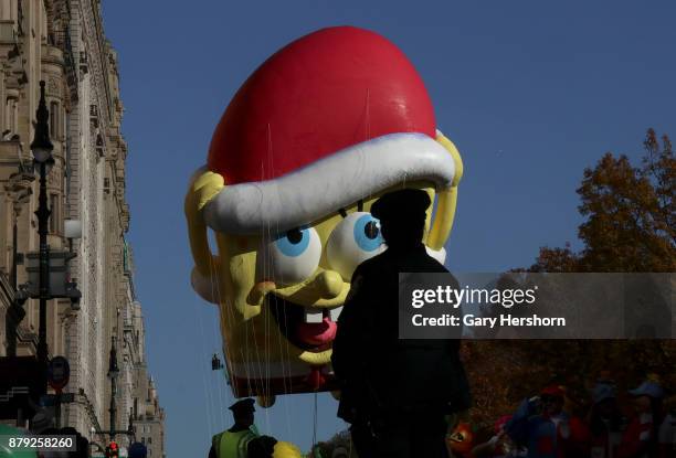 The SpongeBob SquarePants balloon floats past a police officer on Central Park West during the annual Thanksgiving Day Parade on November 23, 2017 in...