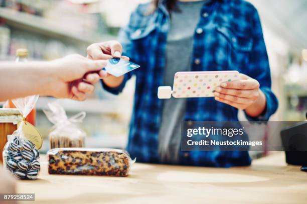 eigentümer halten smartphone während des empfangs kreditkarte vom kunden - neustockimages stock-fotos und bilder